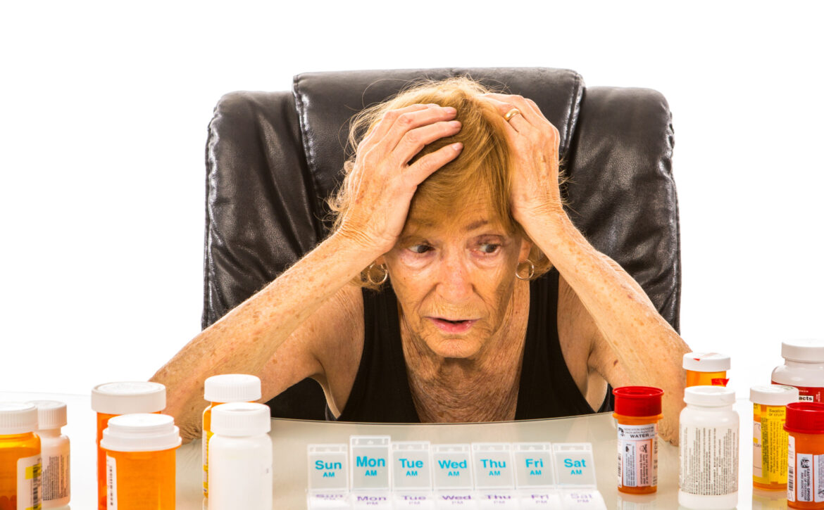 Senior Woman Overwhelmed By Amount Of Pills To Fit Into Her Pill Container