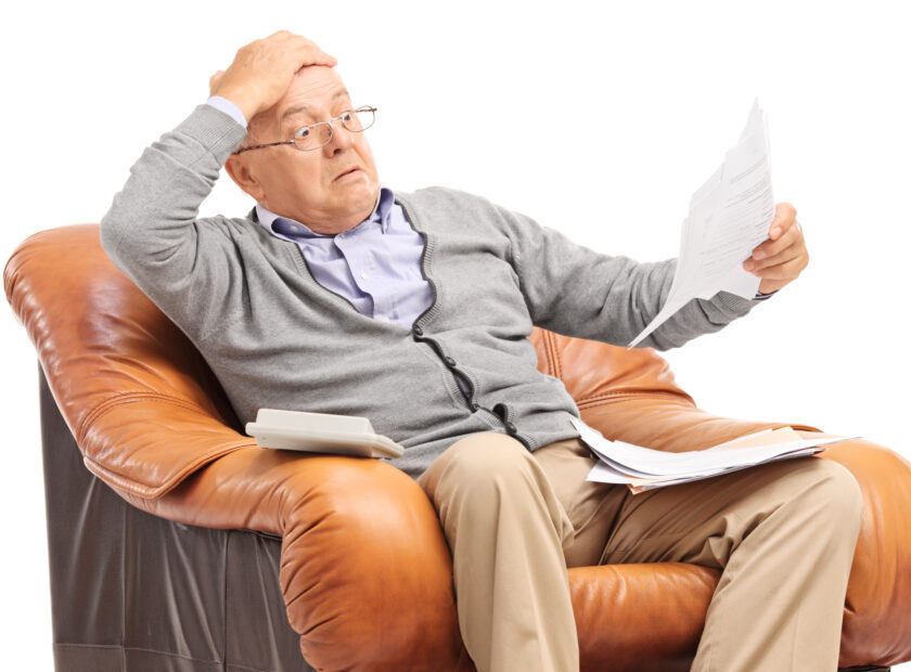 Shocked senior man looking at his bills in disbelief